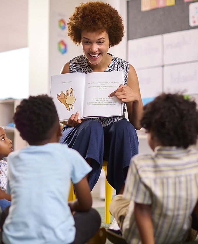 A woman reading a book to a group of children.