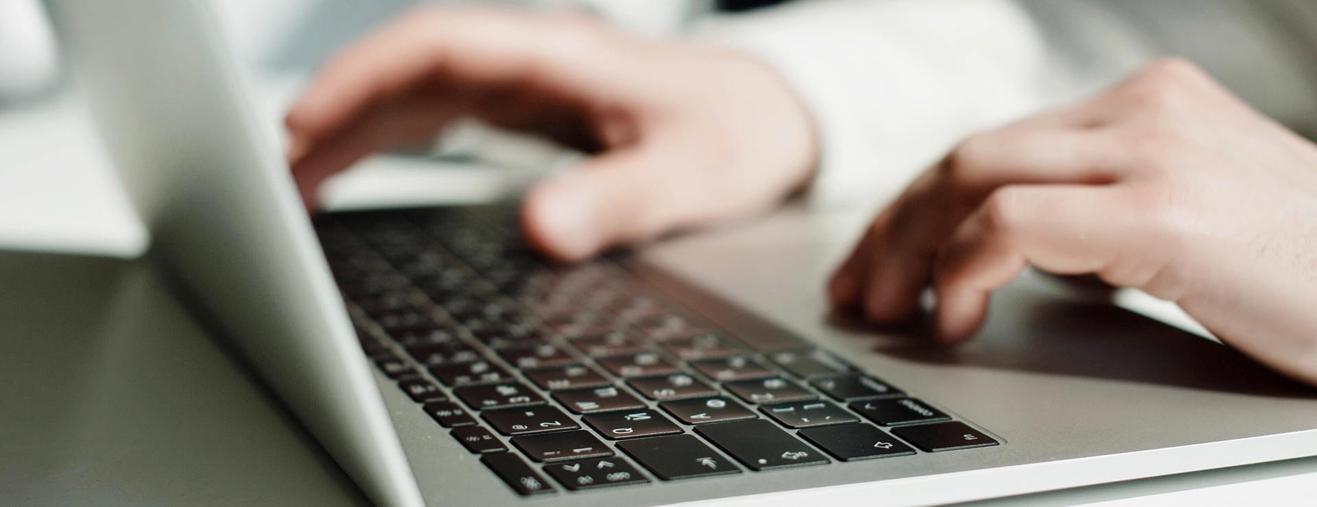 Hands typing on a laptop