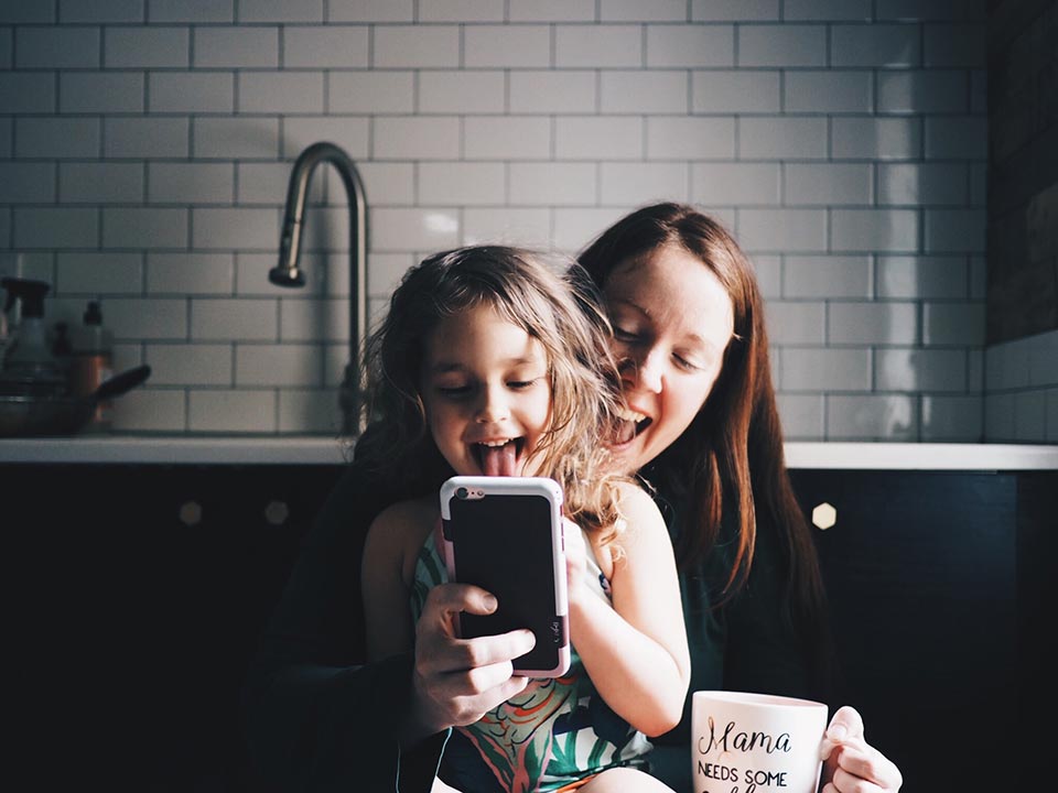 Mom and daughter looking at a smart phone and laughing.