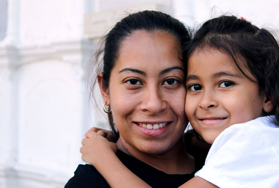 A young girl hugging her mom.