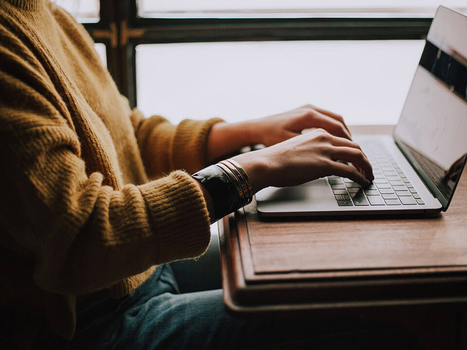 Hands typing on a laptop